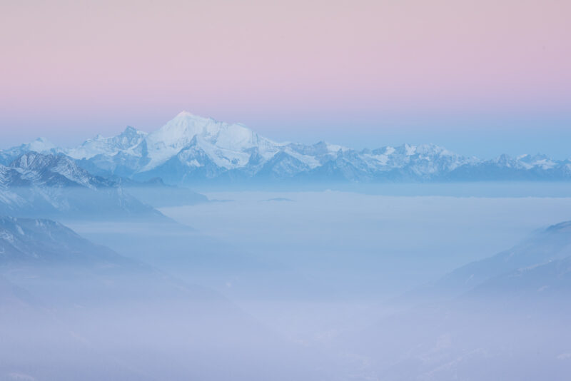 Das frisch verschneite Weisshorn im Wallis erhebt sich über einer Nebeldecke und wird von den ersten Sonnenstrahlen des Morgens beleuchtet.