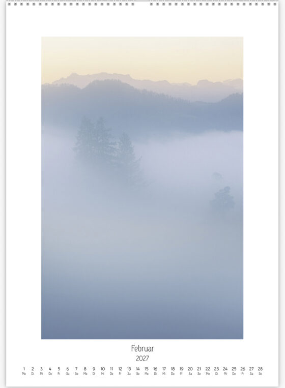Winterlandschaft mit einer teilweise im Nebel verschwindenden Hügelkette und dem Glärnisch im warmen Morgenlicht im Hintergrund.